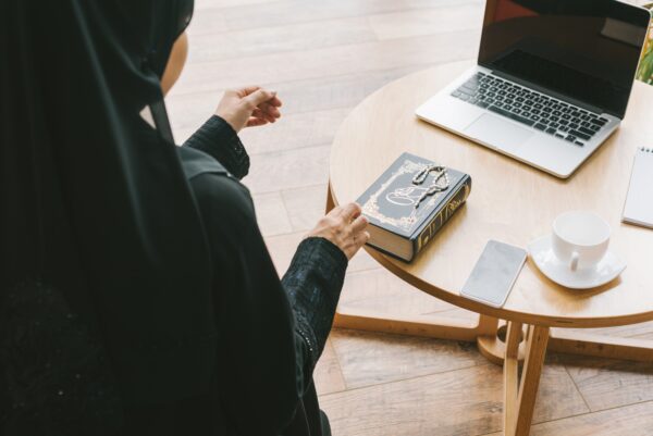 modern muslim woman with quran book and digital devices on table